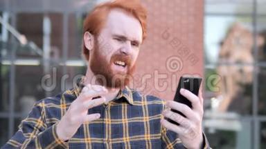 户外红发胡子青年男子在使用智能手机时因失物招领